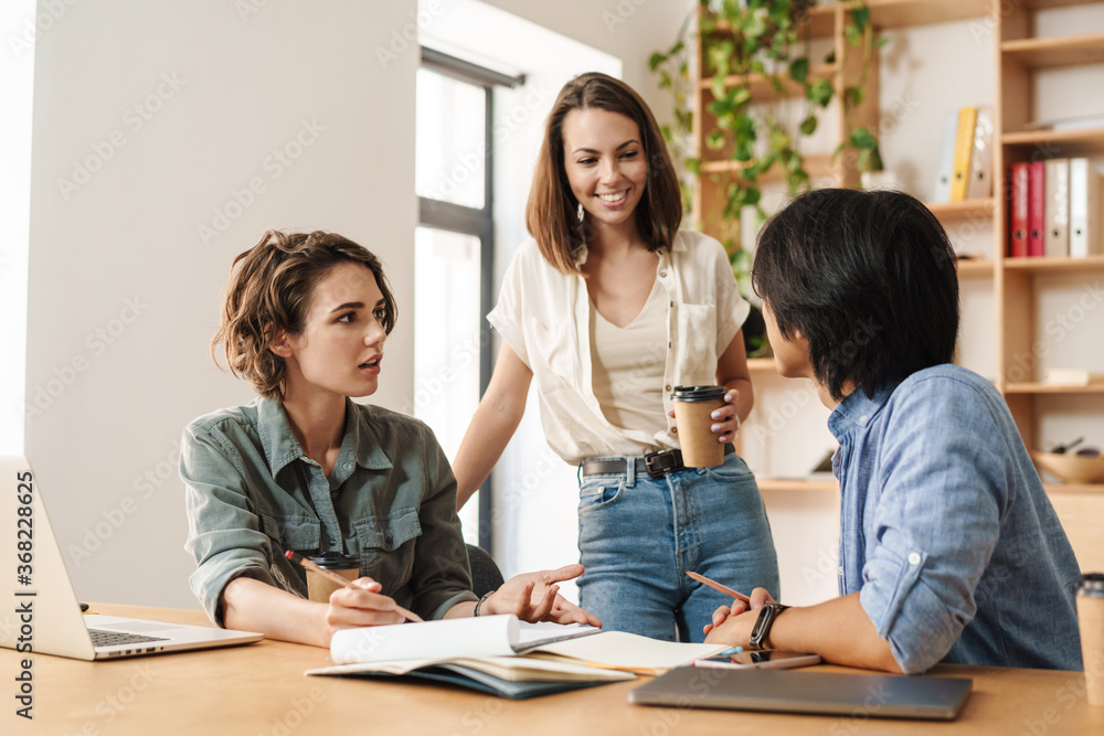 Fototapeta premium Image of colleagues discussing project while working with laptops