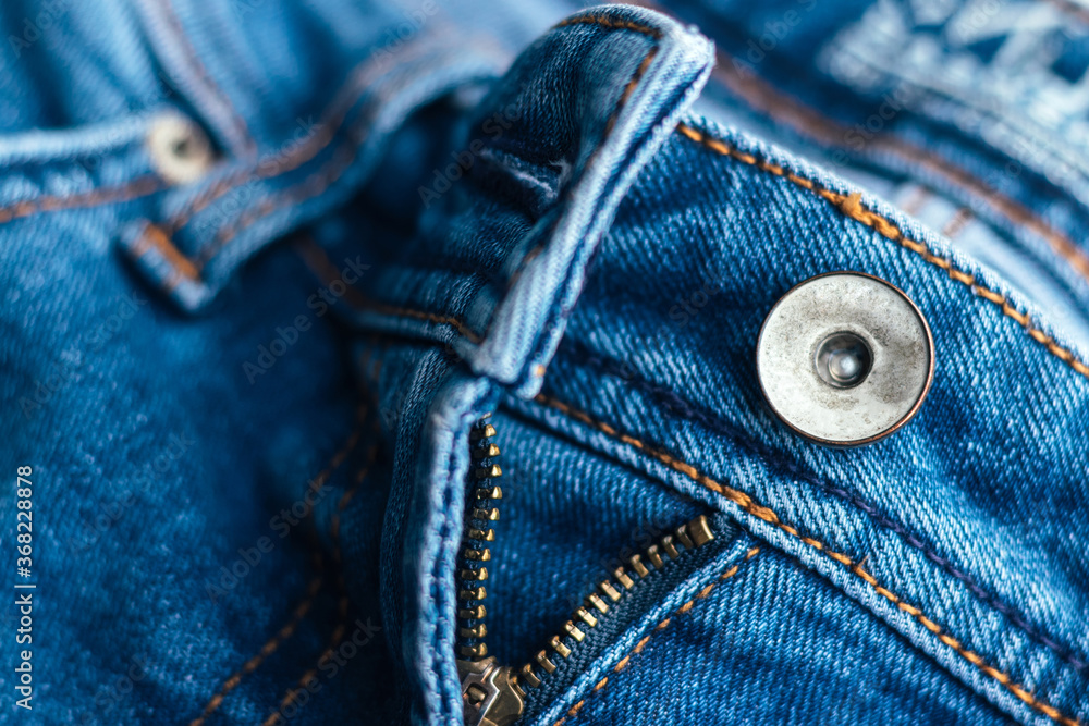 Jeans front with zipper open. Bright blue denim fabric texture background. Closeup view. Selective focus Jeans front with zipper open. Bright blue denim fabric texture background. Closeup view. Selective focus