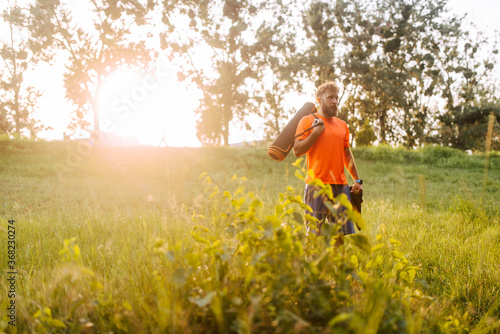 A sports fitness caucasian man in an orange T-shirt goes to training in the forest. Outdoor sports