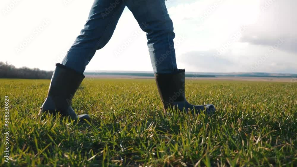 Walking a male farmer on a greenfield. The farmer's feet in boots Walking a male farmer on a greenfield. The farmer's feet in boots