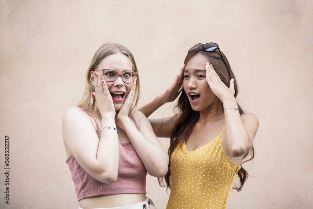 Two girls in front of a pink background Two girls in front of a pink background