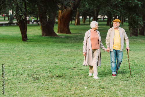 Smiling senior couple holding hands while walking in park