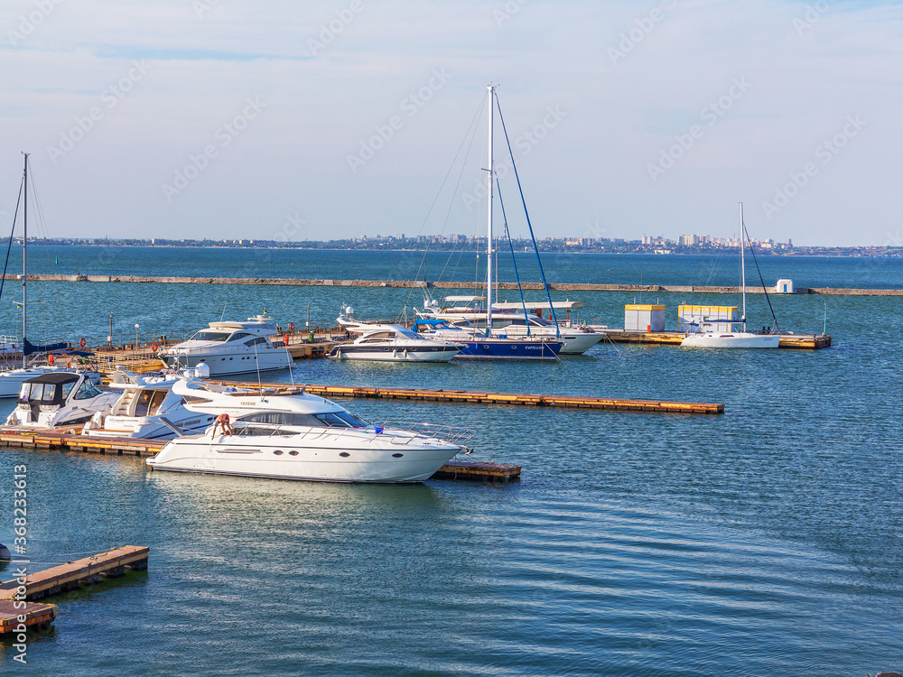 Odessa, Ukraine July 6, 2016: Yacht Club with parked vehicles of various models. Pleasure boat with tourists depart from the pier in Odessa, Ukraine, July 6, 2016