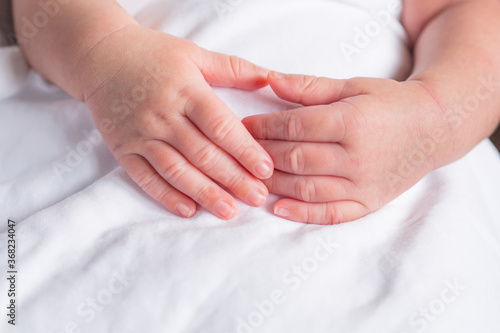 Hands of newborn baby on white cloth