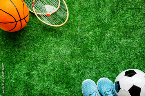Sport games equipment on football field - balls, sneakers, rackets. Top view