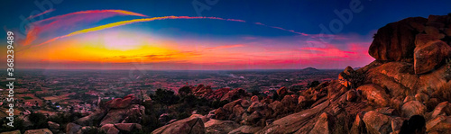 A panoramic view of colorful sky from a hill with stones on the floor