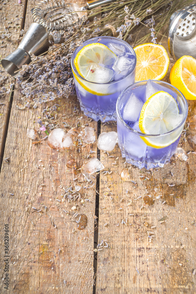 Lavender alcoholic cocktail, Lavandula lemonade with lemon and honey, on wooden background with lavender bunch and barmen utencils, copy space Lavender alcoholic cocktail, Lavandula lemonade with lemon and honey, on wooden background with lavender bunch and barmen utencils, copy space