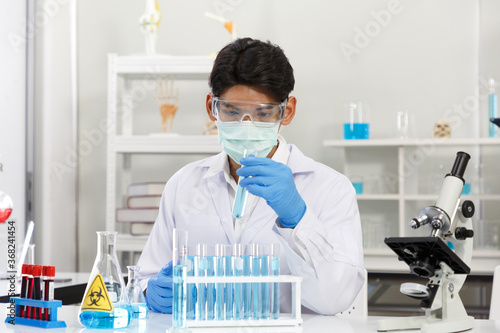 Male Asian Scientist wear Face Mask working in Lab while Checking Solution. SARS-CoV-2 , Covid-19 THEME.