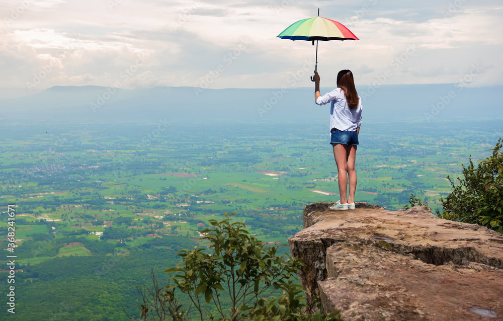 Obraz premium A beautiful woman with an umbrella Standing on the edge of a high cliff
