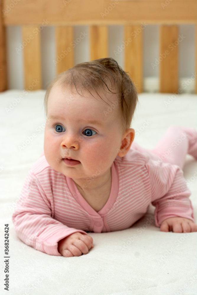 Bbaby girl learning how to lay on tummy. Baby development at 4 month. Education and parenthood. Bbaby girl learning how to lay on tummy. Baby development at 4 month. Education and parenthood.