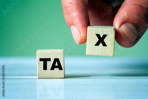 Symbol of tax with word on wooden cube blocks. Hand hold one cube.