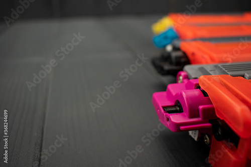 Toner cartridges in magenta, black, cyan and yellow colors on gray wooden background