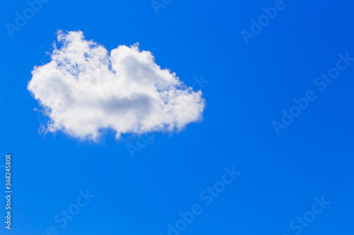 Abstract sky background in blue with one single fluffy soft white cloud and copy space