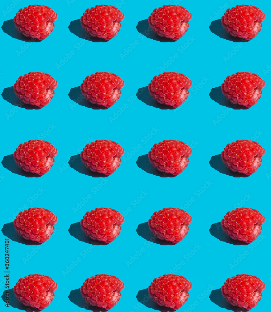 Red raspberry berries on a blue background, repeating pattern Red raspberry berries on a blue background, repeating pattern