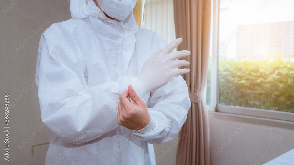 Close-up doctor wearing safety uniform and white surgical glove to protection virus from patient in hospital.