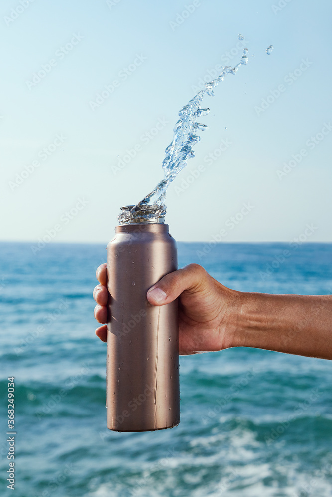 pouring water out of an aluminum reusable bottle - obrazy, fototapety, plakaty 