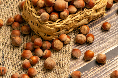 Photos Hazelnuts in a wicker basket and hazelnuts scattered on a background of homespun fabric with a rough texture