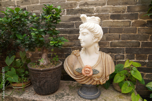 bust of a beautiful girl standing near the wall
