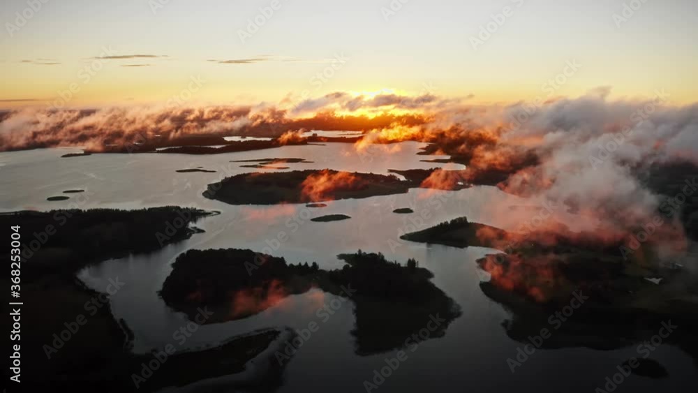 Lake land view from above, drone flies over beautiful islands and low clouds moving in wind backlit with morning sunlight. Aerial, flight over lakes during fantastic sunrise. Warm skyline on horizon Lake land view from above, drone flies over beautiful islands and low clouds moving in wind backlit with morning sunlight. Aerial, flight over lakes during fantastic sunrise. Warm skyline on horizon