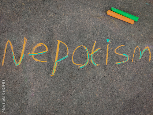 The inscription on the grey board "NEPOTISM". Using color chalk pieces.