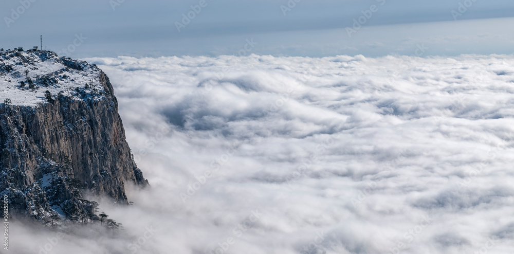 The snow plateau rises above the dense fog, horizontally panoramic