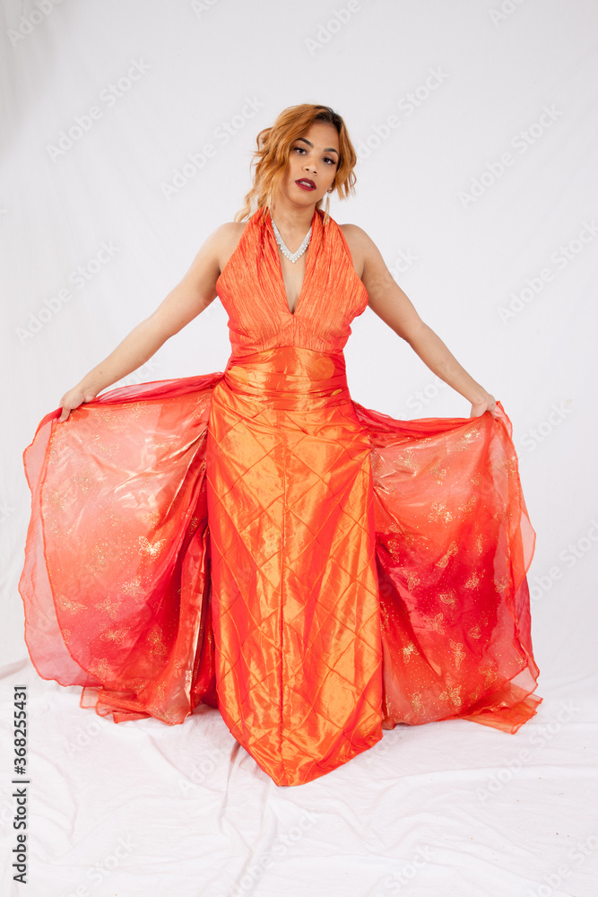 Pretty Hispanic woman playing with her flowing orange dress Pretty Hispanic woman playing with her flowing orange dress