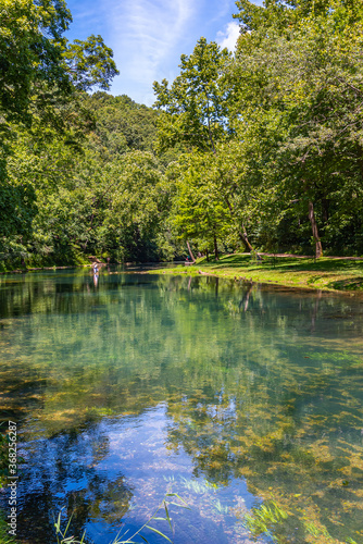 Beautiful clear river flowing through the woods with hiking trail in park