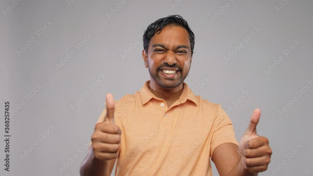 people and furniture concept - portrait of happy smiling young indian man with crossed arms showing thumbs up over grey background people and furniture concept - portrait of happy smiling young indian man with crossed arms showing thumbs up over grey background