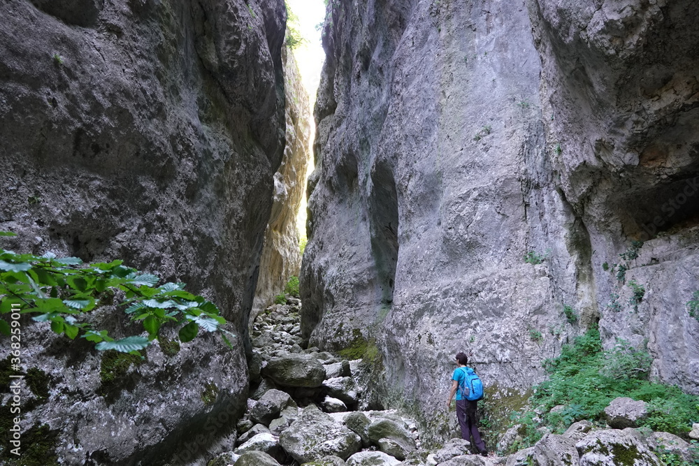 person walking between high rocks on a riverbed