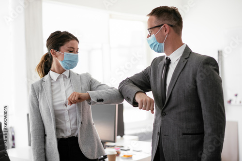 Businessman and businesswoman with medical mask in office. Greetings in Covid-19 time..