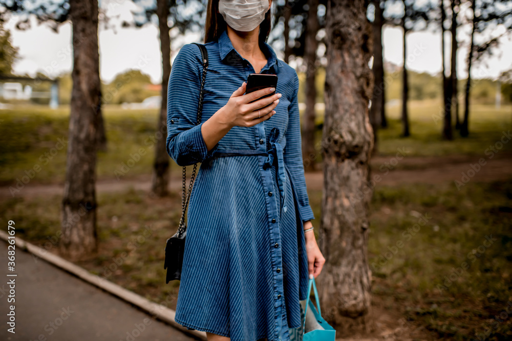Woman with face mask walking down the street using phone Woman with face mask walking down the street using phone