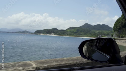 車の窓からドアミラーと海を眺める