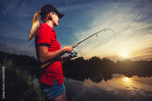 Cute woman is fishing with rod on lake photo