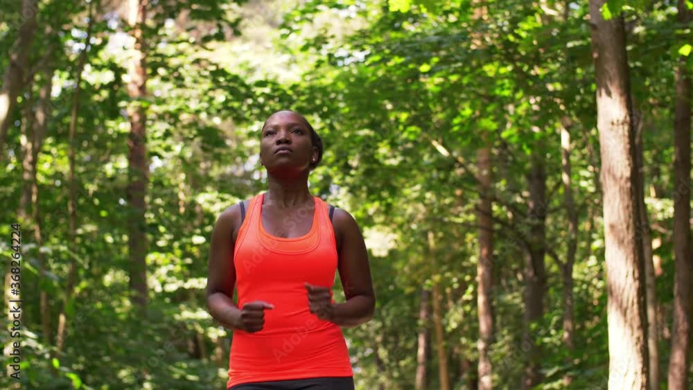fitness, sport and healthy lifestyle concept - young african american woman running in forest fitness, sport and healthy lifestyle concept - young african american woman running in forest