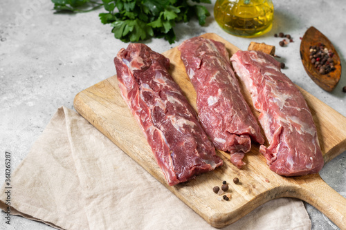 Lamb meat. Young lamb meat on a wooden Board on the light gray kitchen table. Raw lamb meat and cooking ingredients. Lamb tenderloin