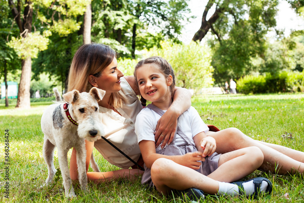 Obraz premium young pretty caucasian mother walking with little cute daughter and dog fox terrier, lifestyle people concept