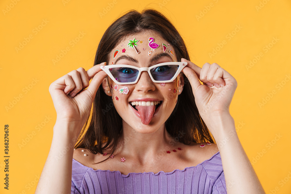 Image of joyful woman wearing sunglasses showing her tongue Image of joyful woman wearing sunglasses showing her tongue