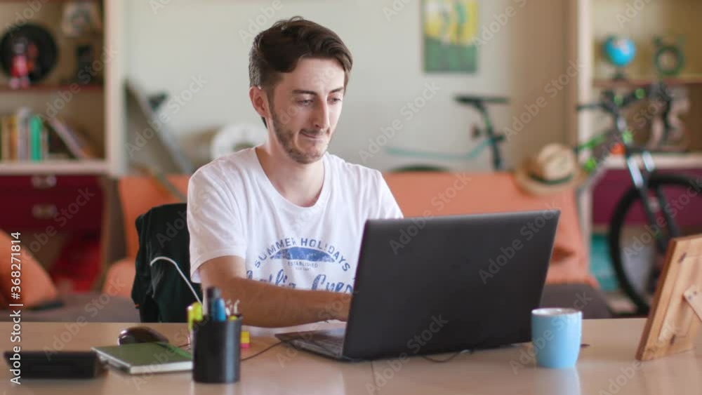 The guy is sitting at a table and writing on a laptop The guy is sitting at a table and writing on a laptop