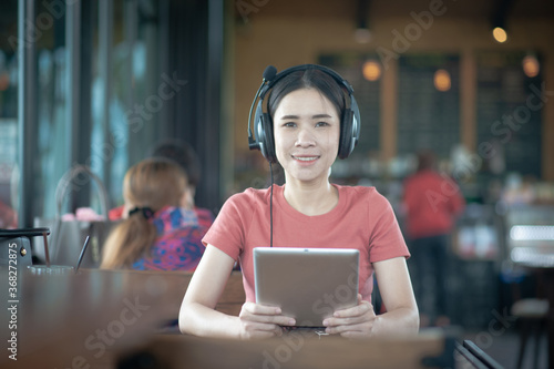 Asian women using tablet listening music sitting cafe,concept people business technology lifestyle