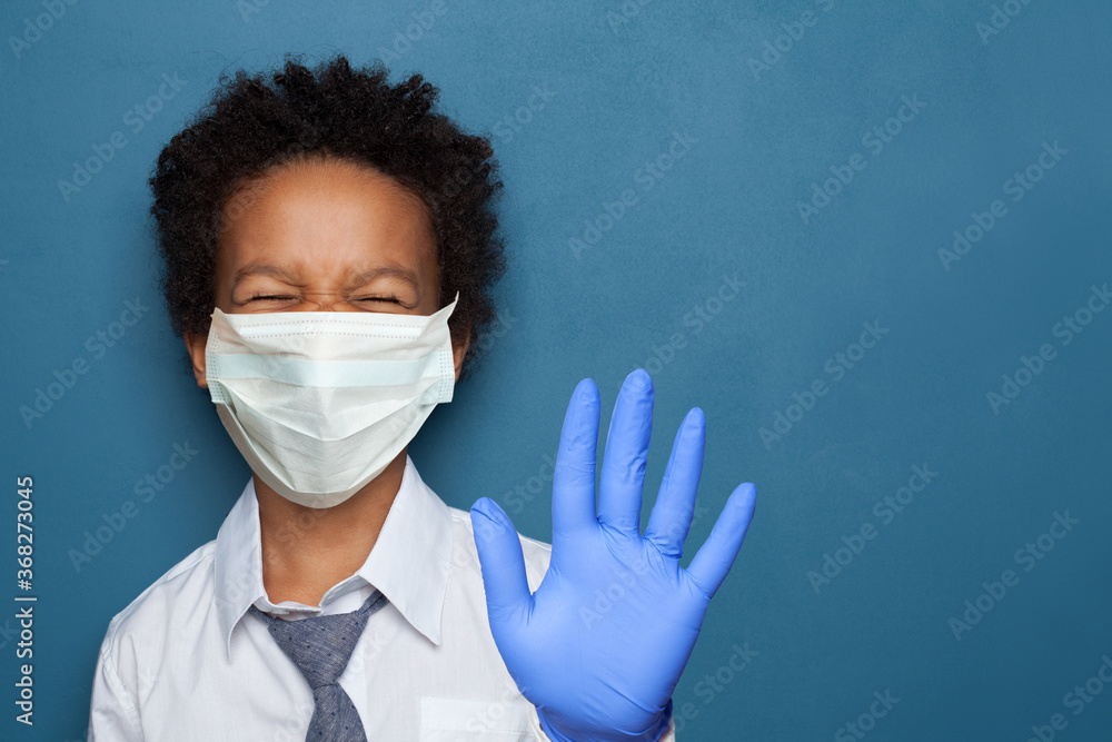 Funny black child in protective medical face mask showing stop gesture Funny black child in protective medical face mask showing stop gesture
