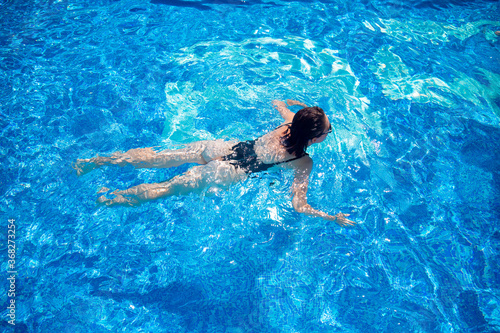 Woman black swimsuit swimming on blue water pool hotel  top view