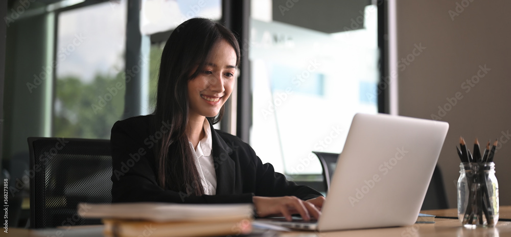 A businesswoman is using a computer laptop while sitting at the working desk. A businesswoman is using a computer laptop while sitting at the working desk.