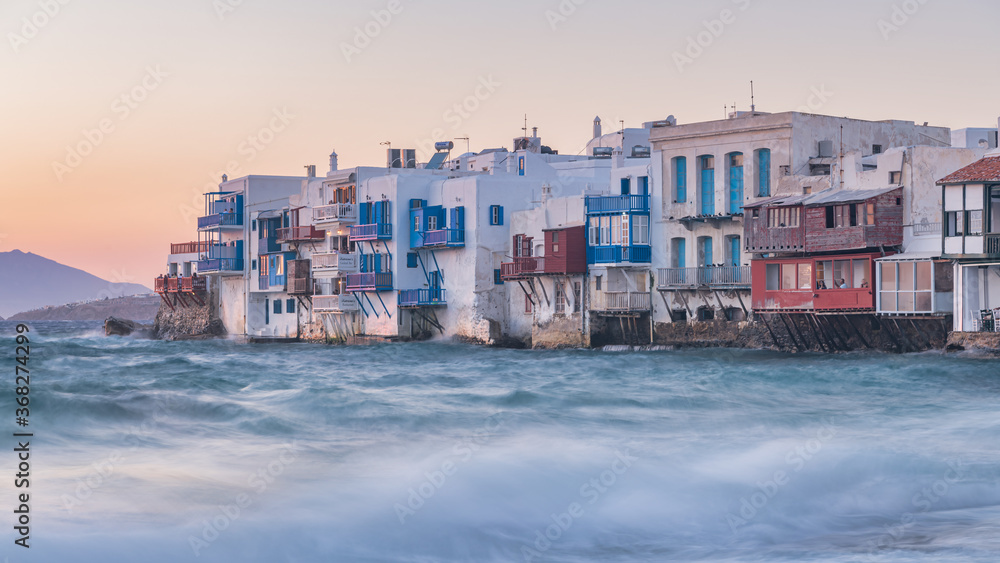 The Little Venice district with old colorful houses by the sea in Mykonos Island at sunset, Cyclades, Greece. Greek landscape (100 matches). Travel and tourism concept.