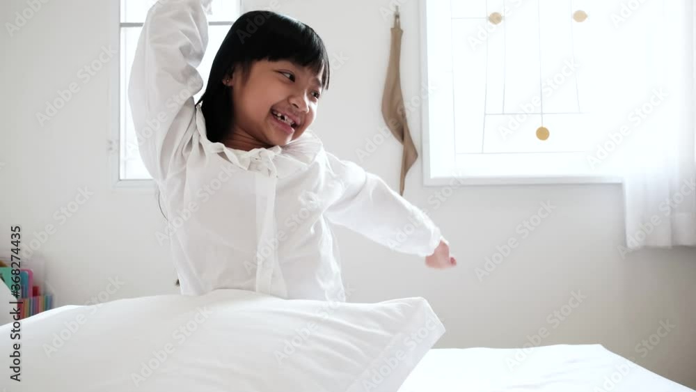 Asian child girl stretches after waking up in her bedroom Asian child girl stretches after waking up in her bedroom