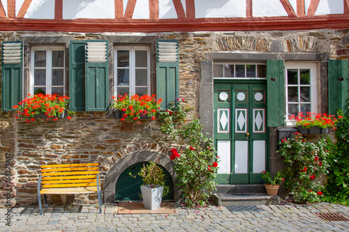 Facade of an old half-timbered house with flowers and a bench in front © jokuephotography