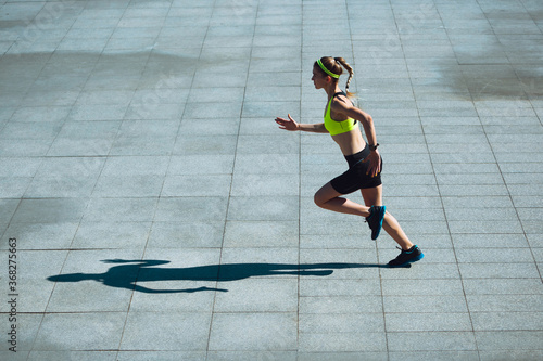 Achievement. Female runner, athlete training outdoors. Professional runner, jogger working out on the street. Concept of healthy lifestyle, sport, wellness, wellbeing, motion and action, activity.