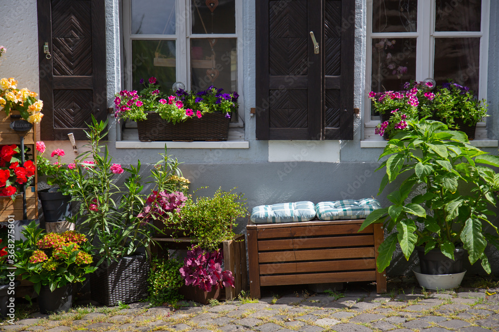Facade of an old house with flowers and a bench in front