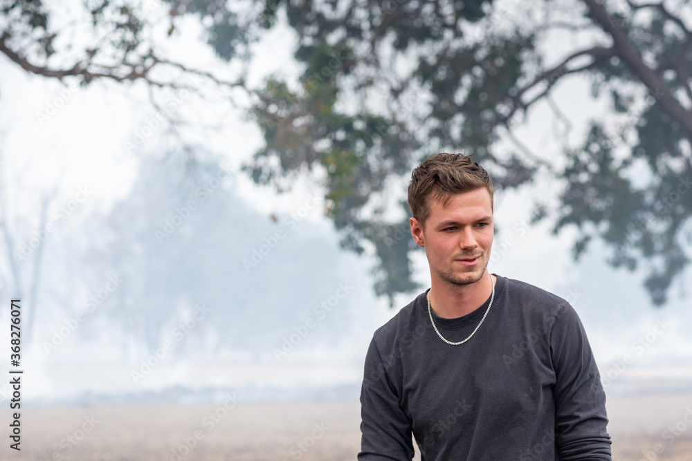 Young man outdoors with smoke in the background Young man outdoors with smoke in the background