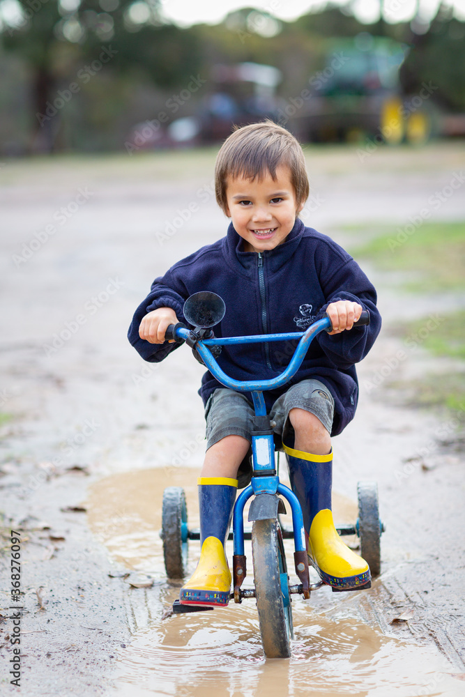 Kid riding a tricycle in puddle Kid riding a tricycle in puddle