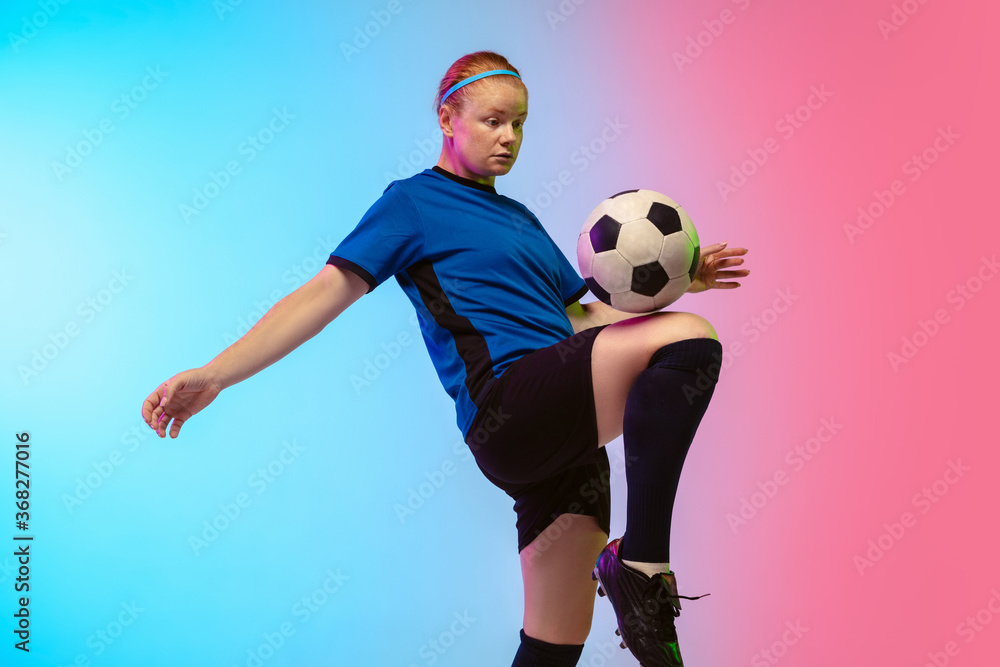 Bouncing ball. Female soccer, football player training in action isolated on gradient studio background in neon light. Concept of motion, action, ahievements, healthy lifestyle. Youth culture.